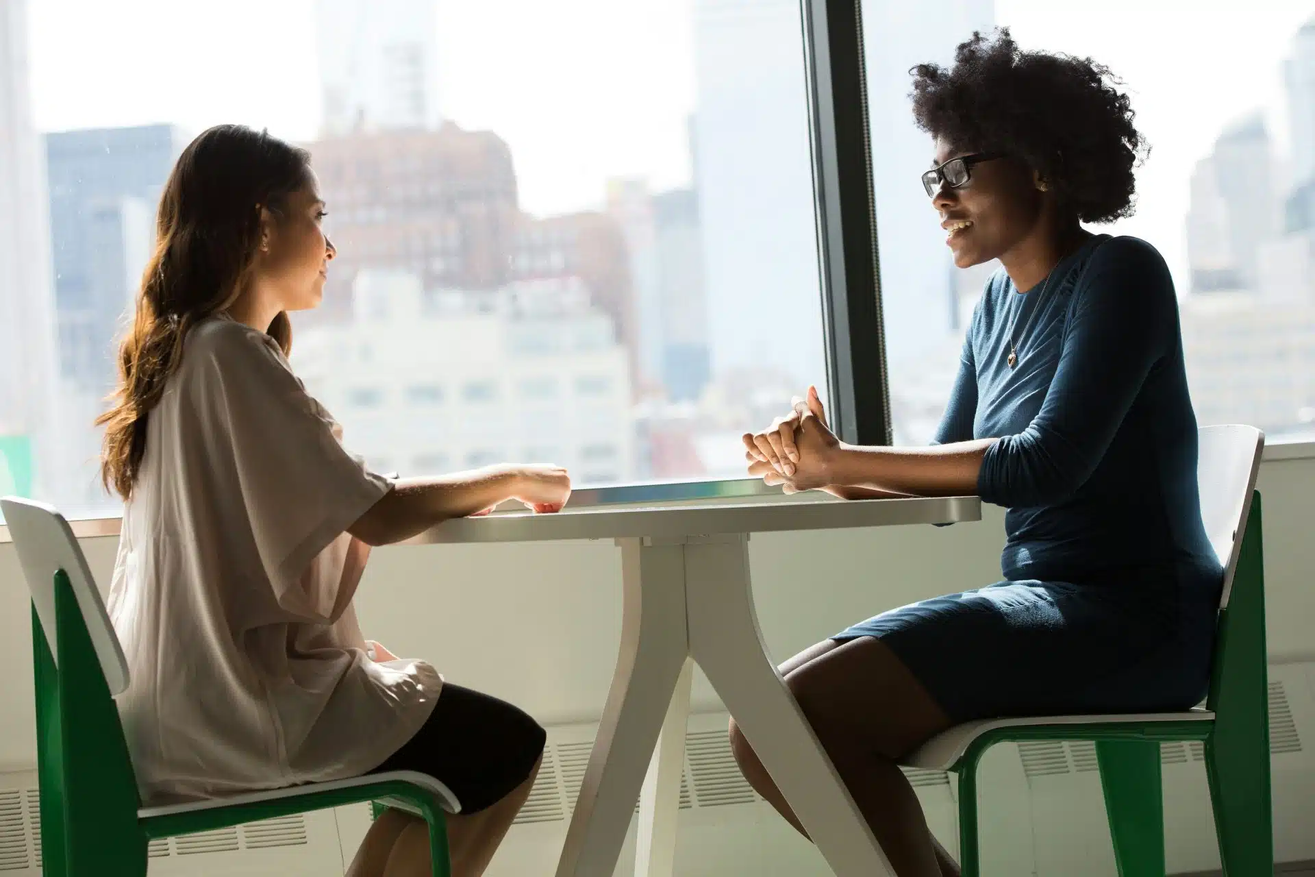 Two women sit at a table for a remote work interview