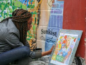Nile Livingston providing the finishing details for her mural to honor farmers on behalf of the brand, Sunkist. 