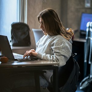 Woman working late on her laptop at a desk in a dimly lit office